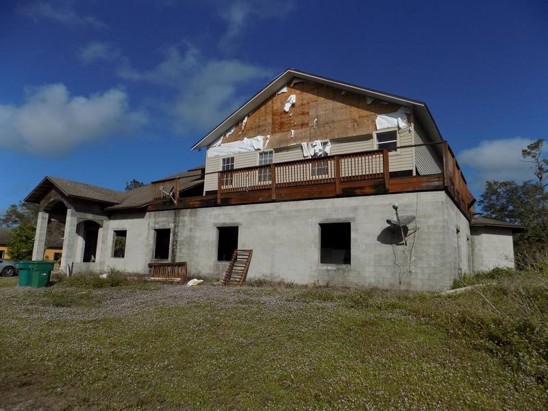 Farmhouse with hurricane damage to the roof and upper-story wall