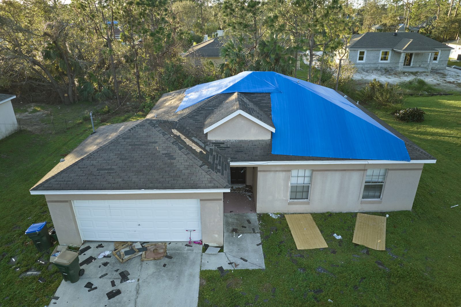 Aerial view of a Central Florida home with a blue tarp over hurricane roof damage