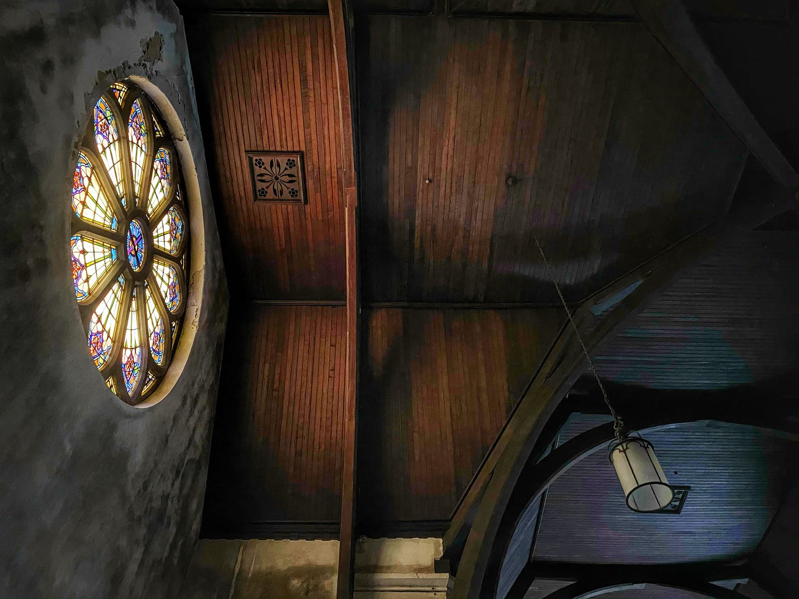 Smoke-stained church interior with a stained-glass rose window