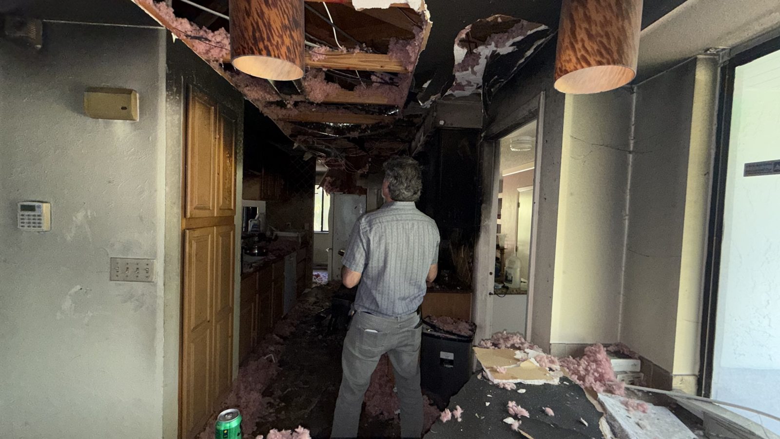 Collapsed ceiling with insulation hanging inside a storm-damaged home