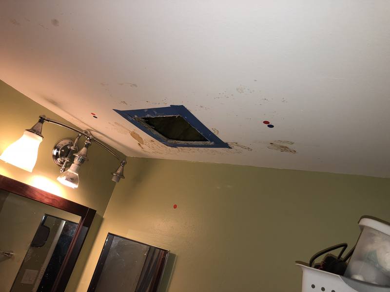Water stains on a condo unit's ceiling around an access panel after hurricane damage