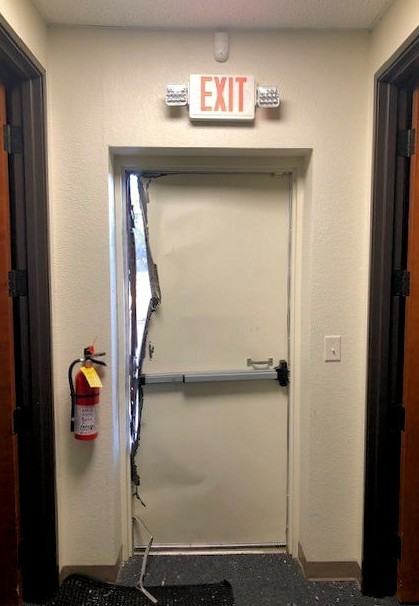 Forced-open exit door with damaged frame at a condo or HOA association building