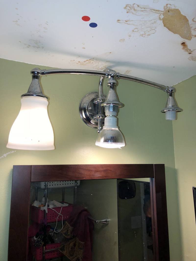 Water-stained wall above a bathroom vanity from a leak in the unit above