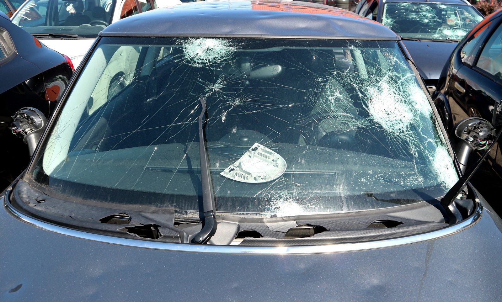 Hail-shattered windshield on a car in a dealership lot