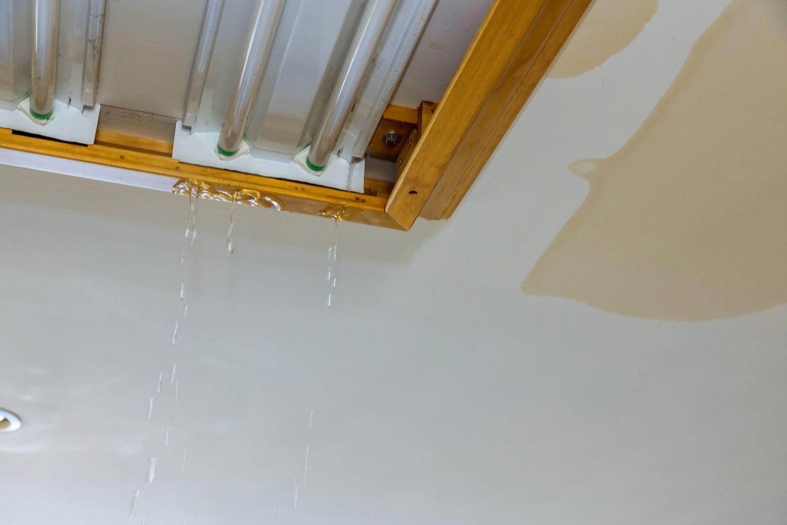 Water dripping from a dental office ceiling light fixture, with a spreading brown stain
