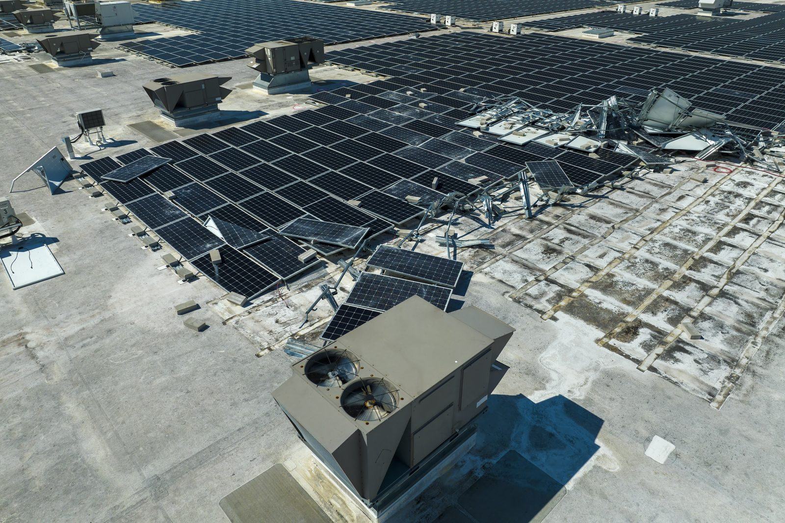 Destroyed rooftop solar array on an industrial building after a storm