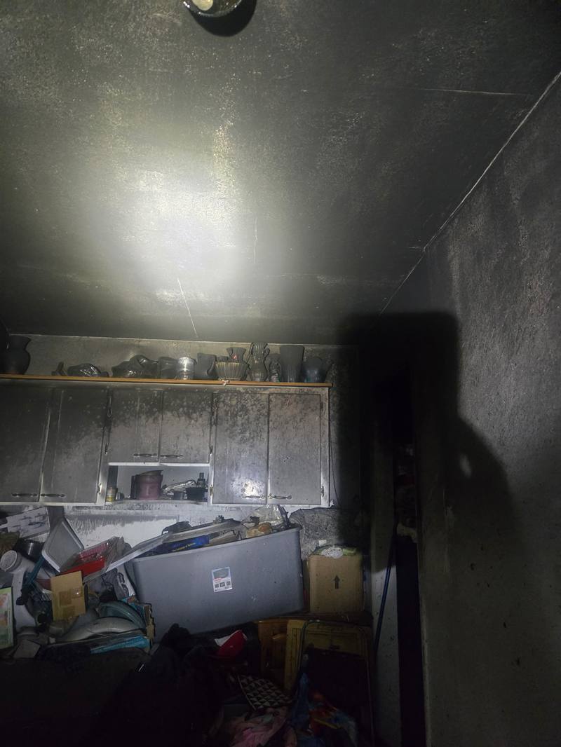 Soot-covered kitchen cabinets and contents after a house fire