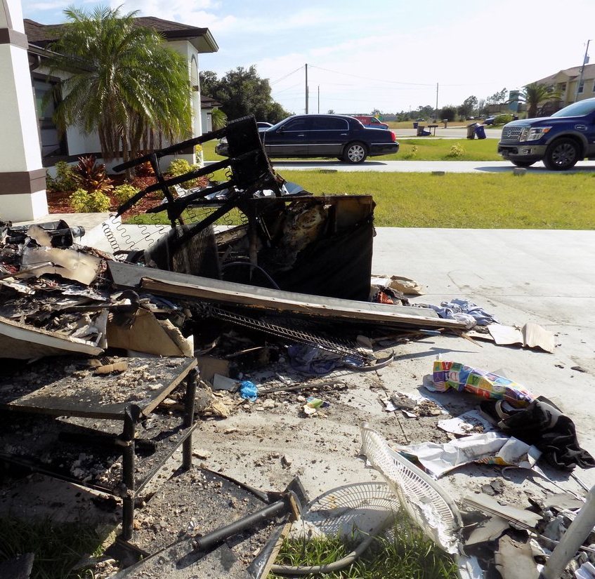 Fire-damaged furniture and belongings set out at the curb after a neighbor's fire