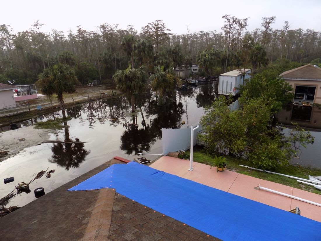 Floodwater across yards and a tarped roof after a storm — the kind of claim Homeland handles for Pensacola, FL property owners