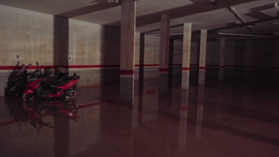 Flooded underground parking garage with water covering the floor around parked scooters