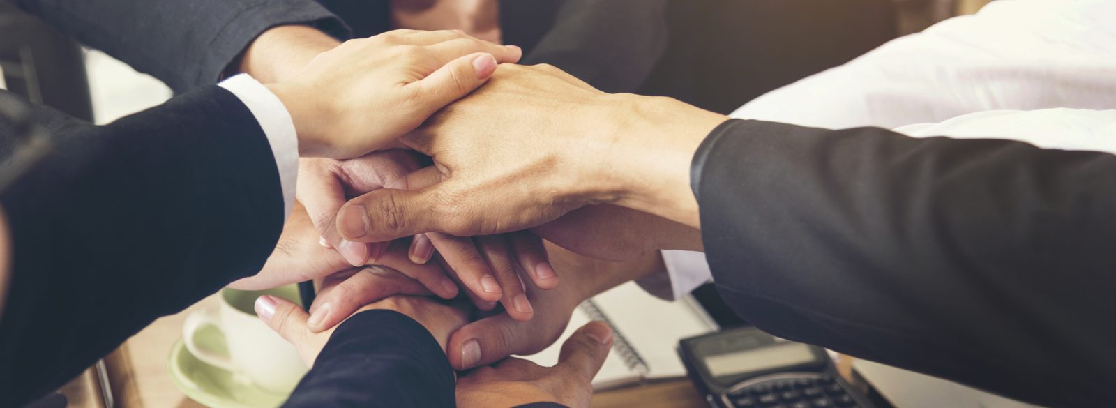 Homeland Public Adjusters team members stacking hands together