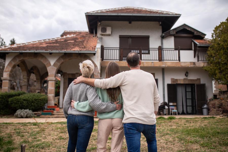 A family standing arm in arm outside their home