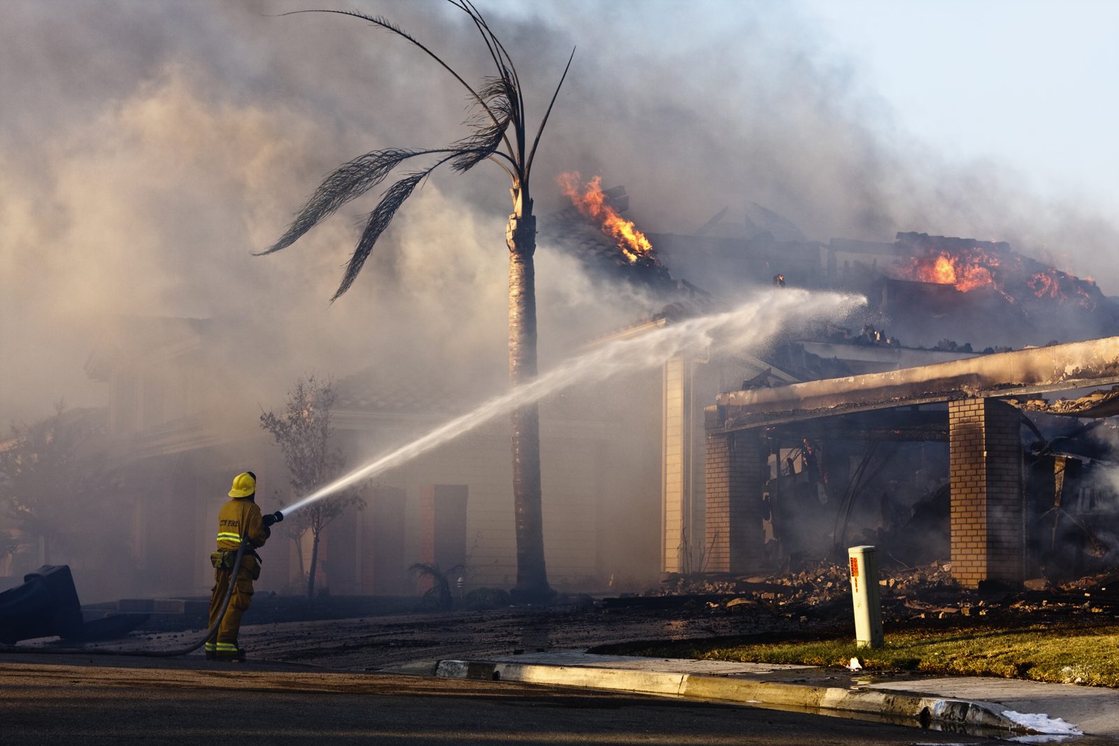Firefighter spraying water on a burning Florida home