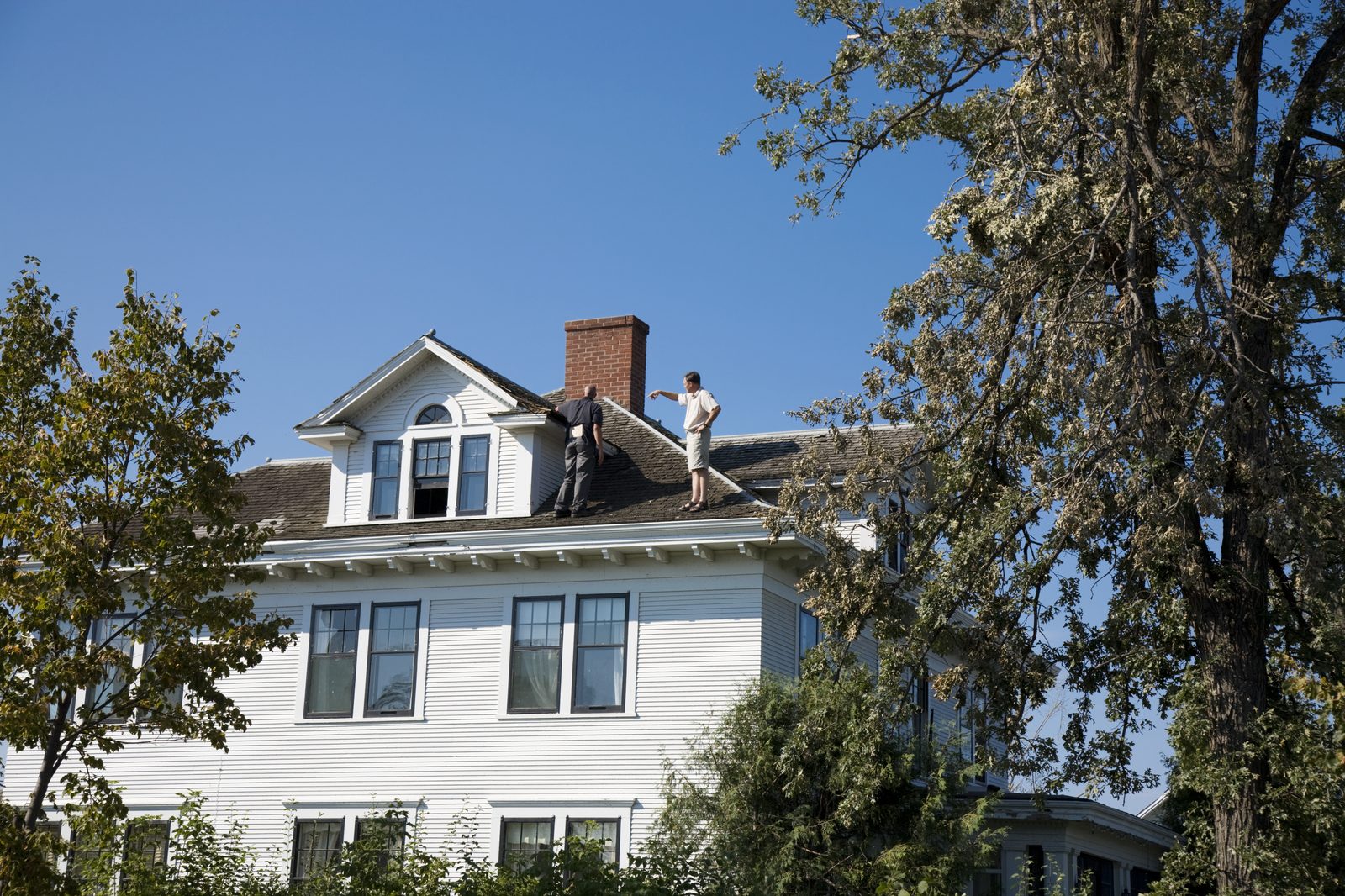 Two-story house with a damaged roof after a tree came down in a storm