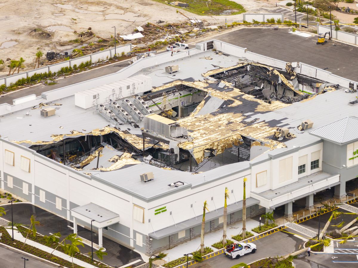 Aerial view of a torn-open commercial building roof after hurricane damage in Florida