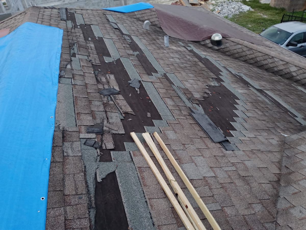 Tarped roof after storm damage removed shingles at a home in Naples, FL