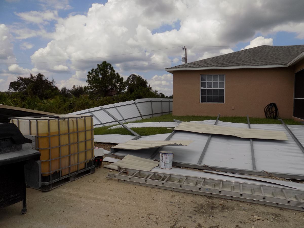 Collapsed carport structure from storm damage at a rental property in Belle Glade, FL