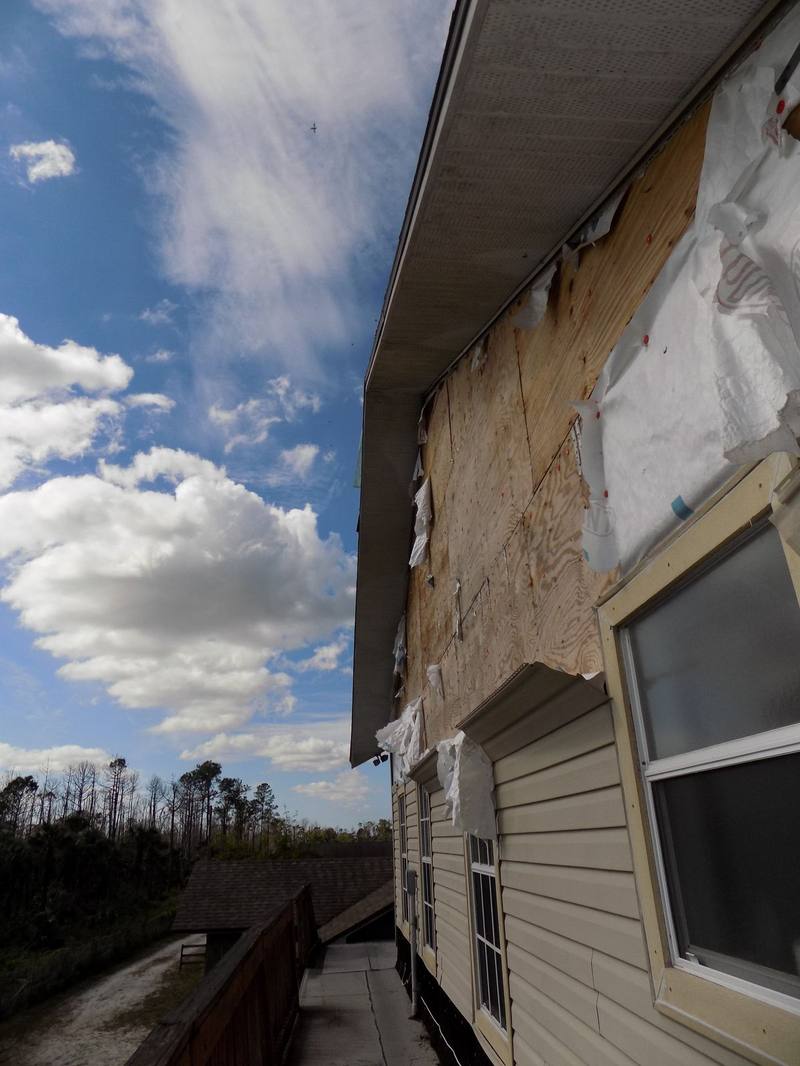 Wind-torn siding exposing wall sheathing on a home exterior