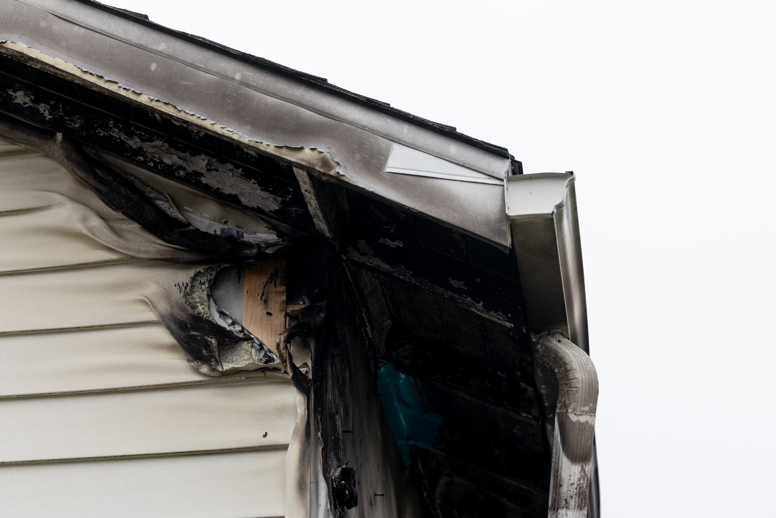 Scorched and melted vinyl siding at the corner of a house after a lightning strike