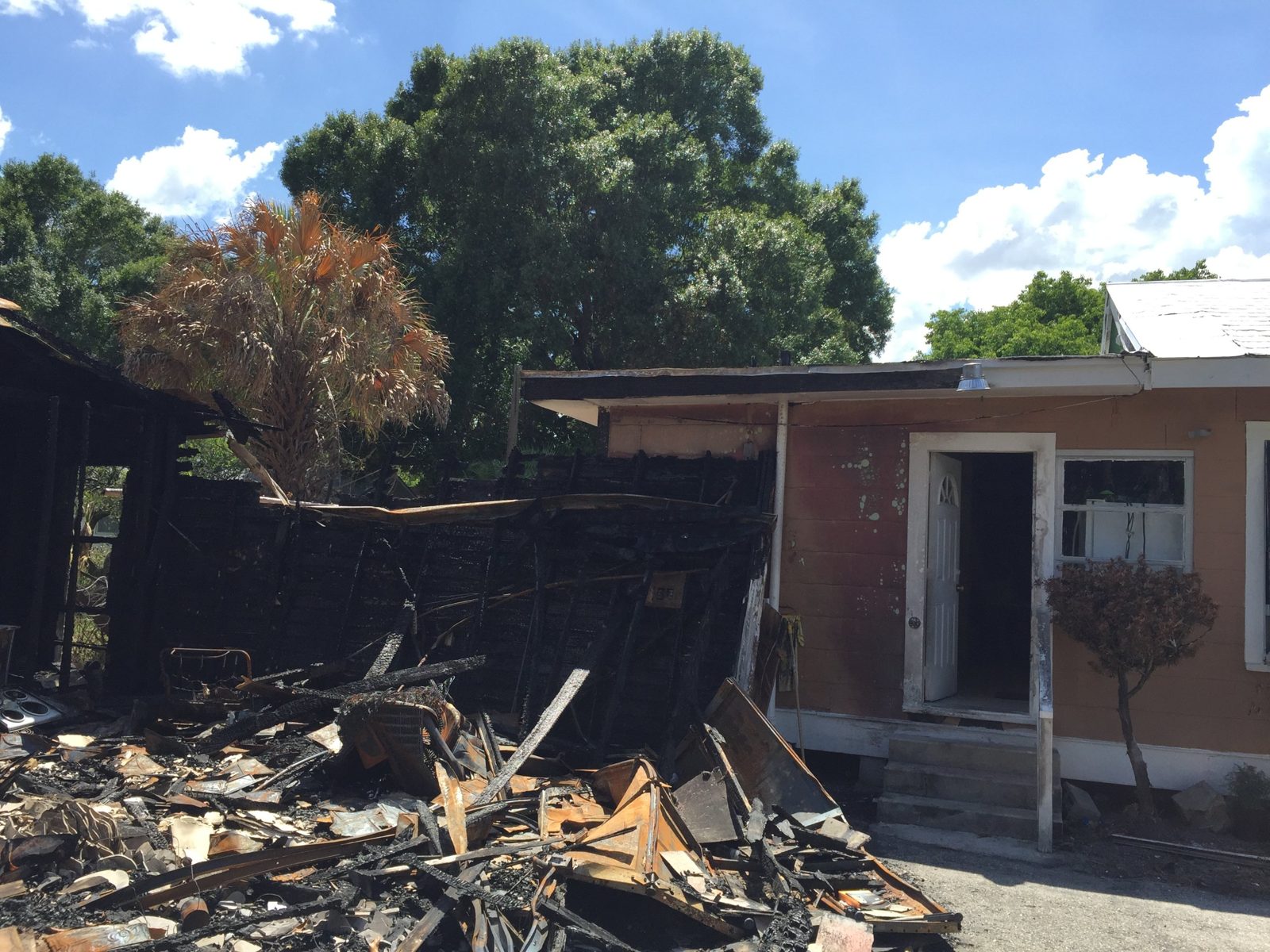 Florida home destroyed by a lithium-ion battery fire, with charred framing and burned debris beside the standing structure