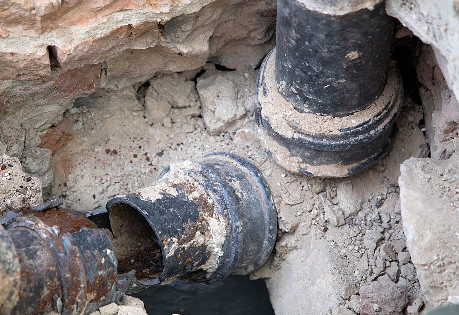 Old corroded cast iron sewer pipes exposed during a plumbing repair