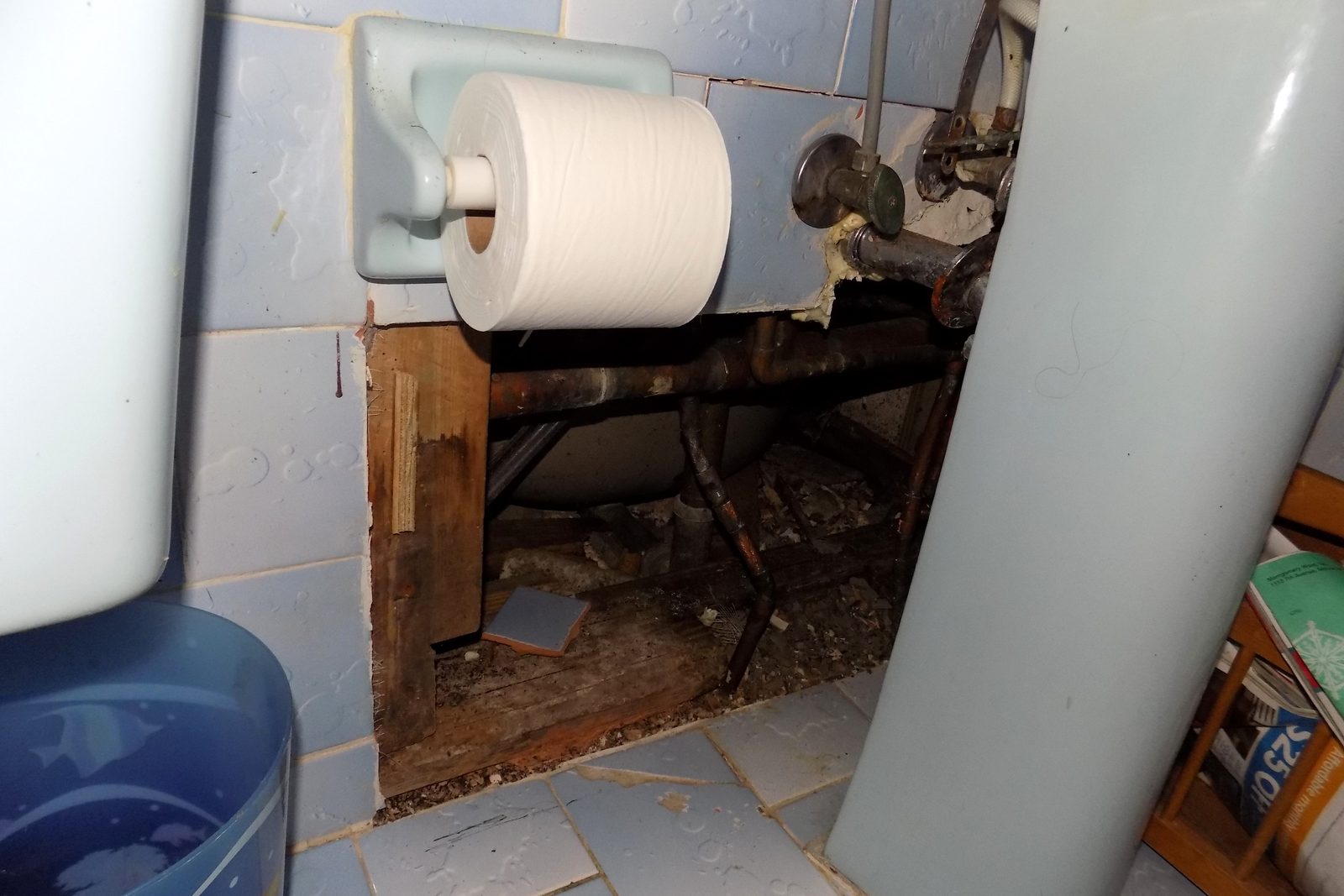 Bathroom wall and floor opened to reach corroded water pipes during a leak repair