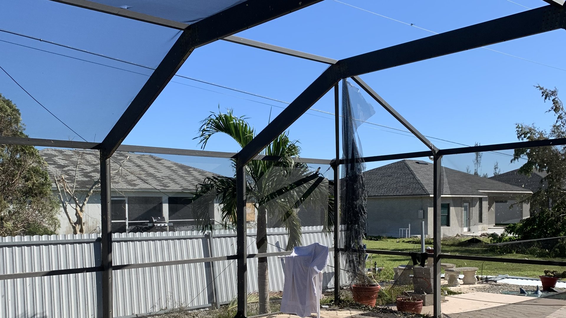 A pool screen enclosure with torn screens after a hurricane in Florida