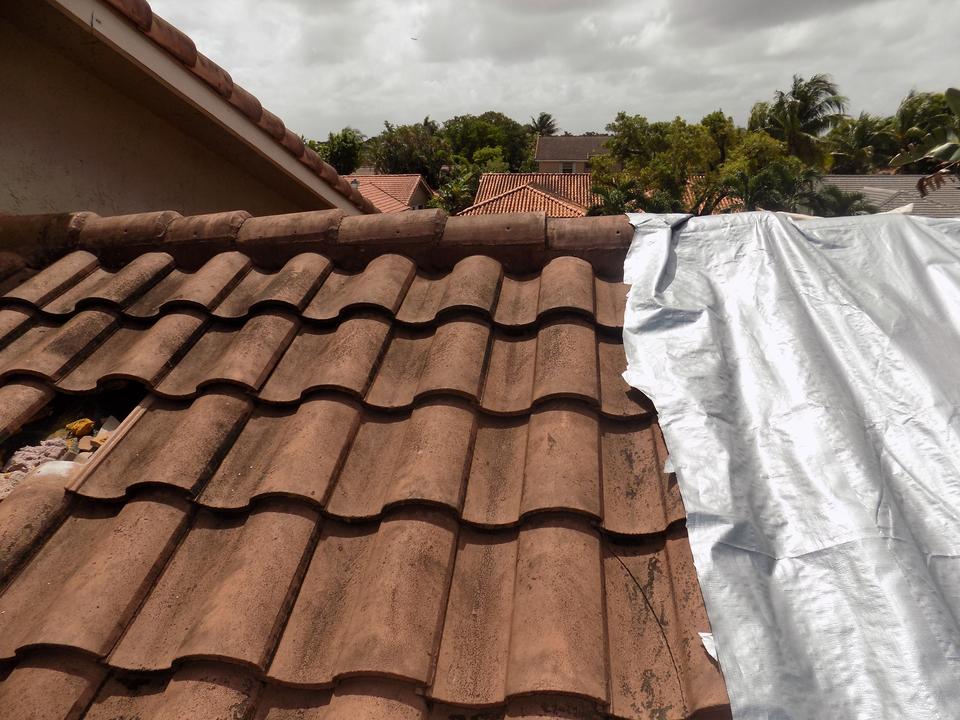 Tile roof with storm damage covered by a tarp at a home in Doral, FL