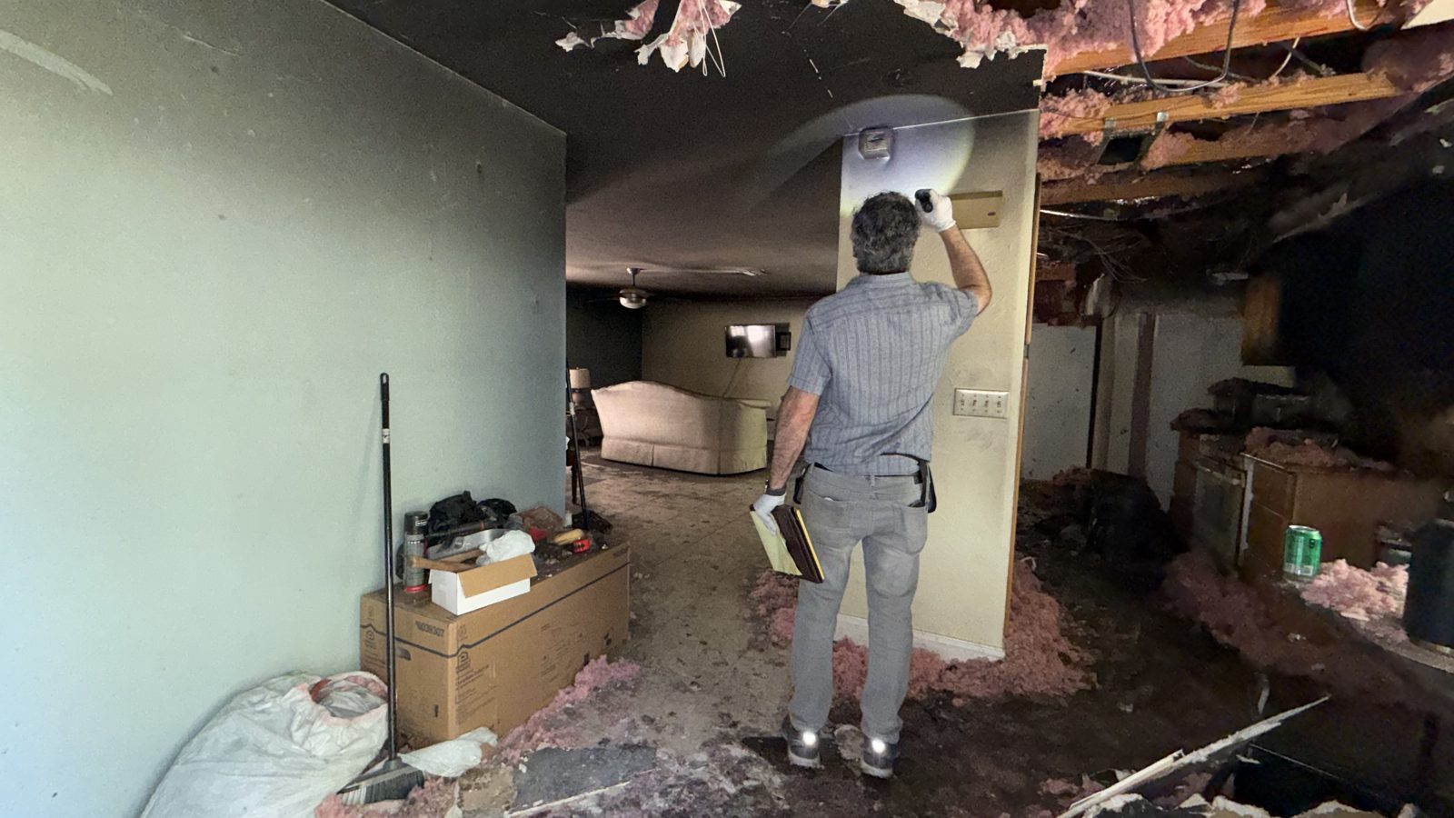 Public adjuster walking through a fire-damaged home with a collapsed ceiling