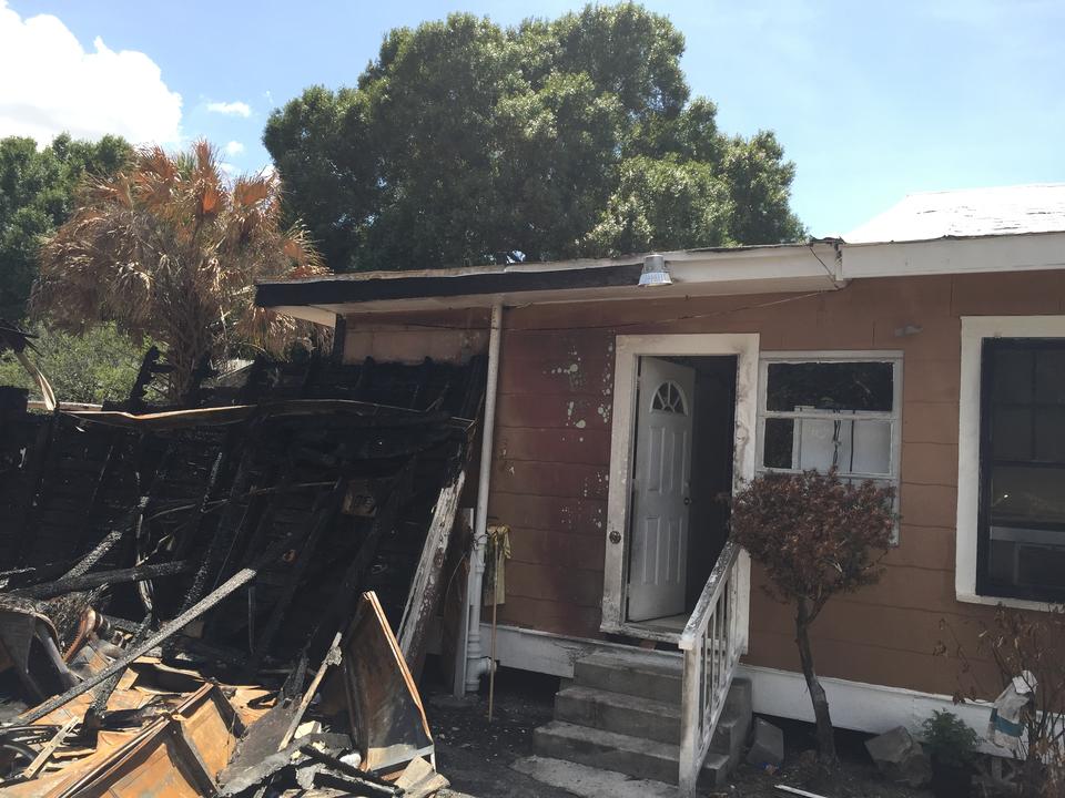 Fire-damaged home exterior with charred debris in Immokalee, FL
