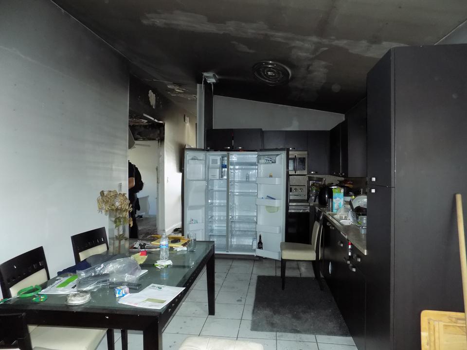 Soot-covered kitchen with a scorched ceiling and refrigerator after a fire at a home in Jupiter, FL