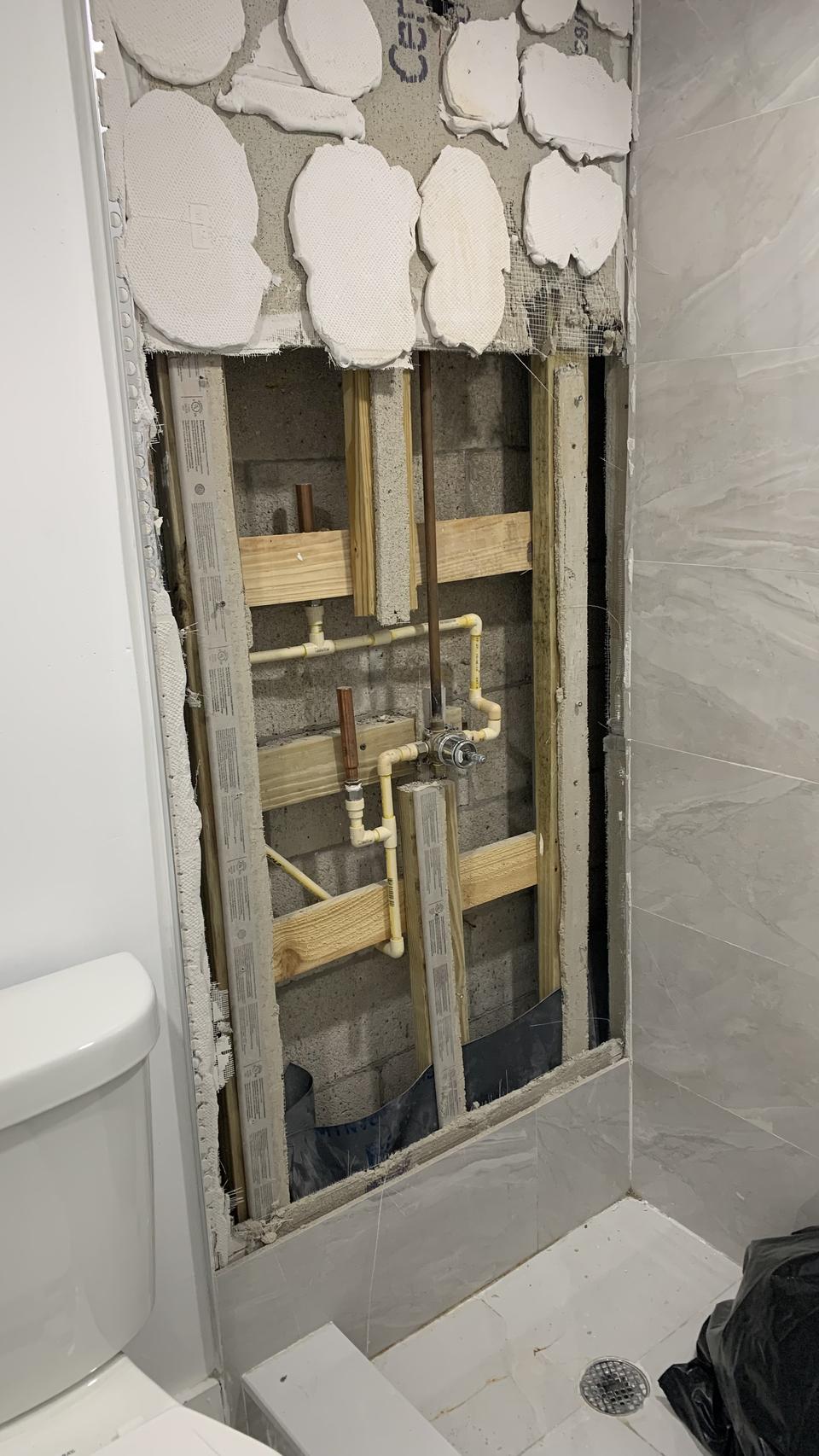 Opened shower wall exposing plumbing during a repair at a home in Kendall, FL
