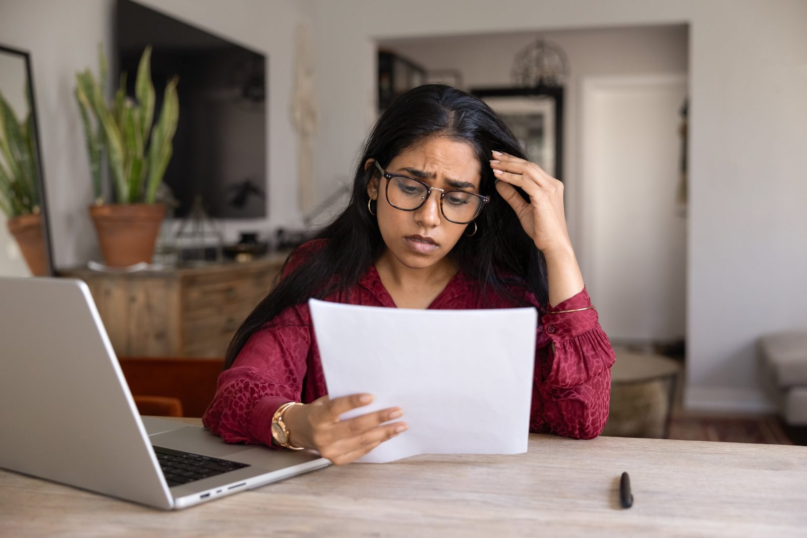 Renter at her kitchen table reading a claim denial letter from her insurance company