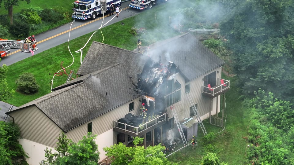Firefighters battling a house fire with smoke rising from the roof