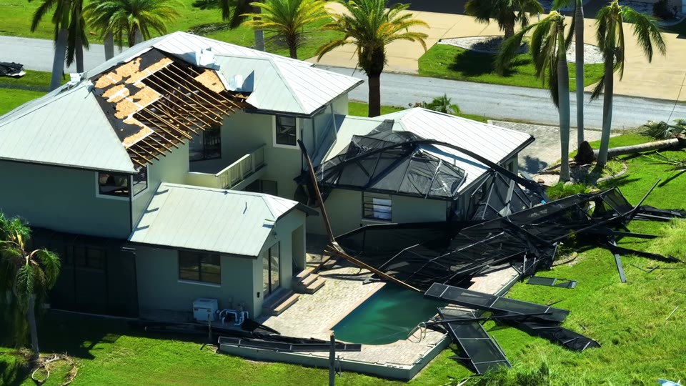 Home with hurricane wind damage, a torn-off roof, and a collapsed pool enclosure