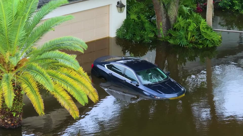 Car partially submerged in floodwater in a residential driveway