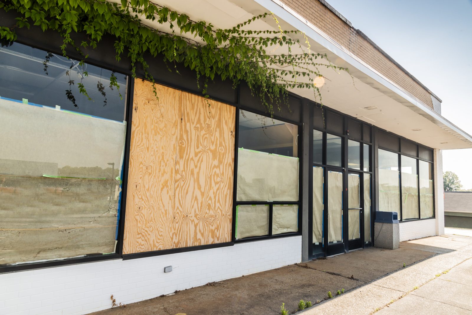 Retail storefront windows boarded with plywood after storm damage