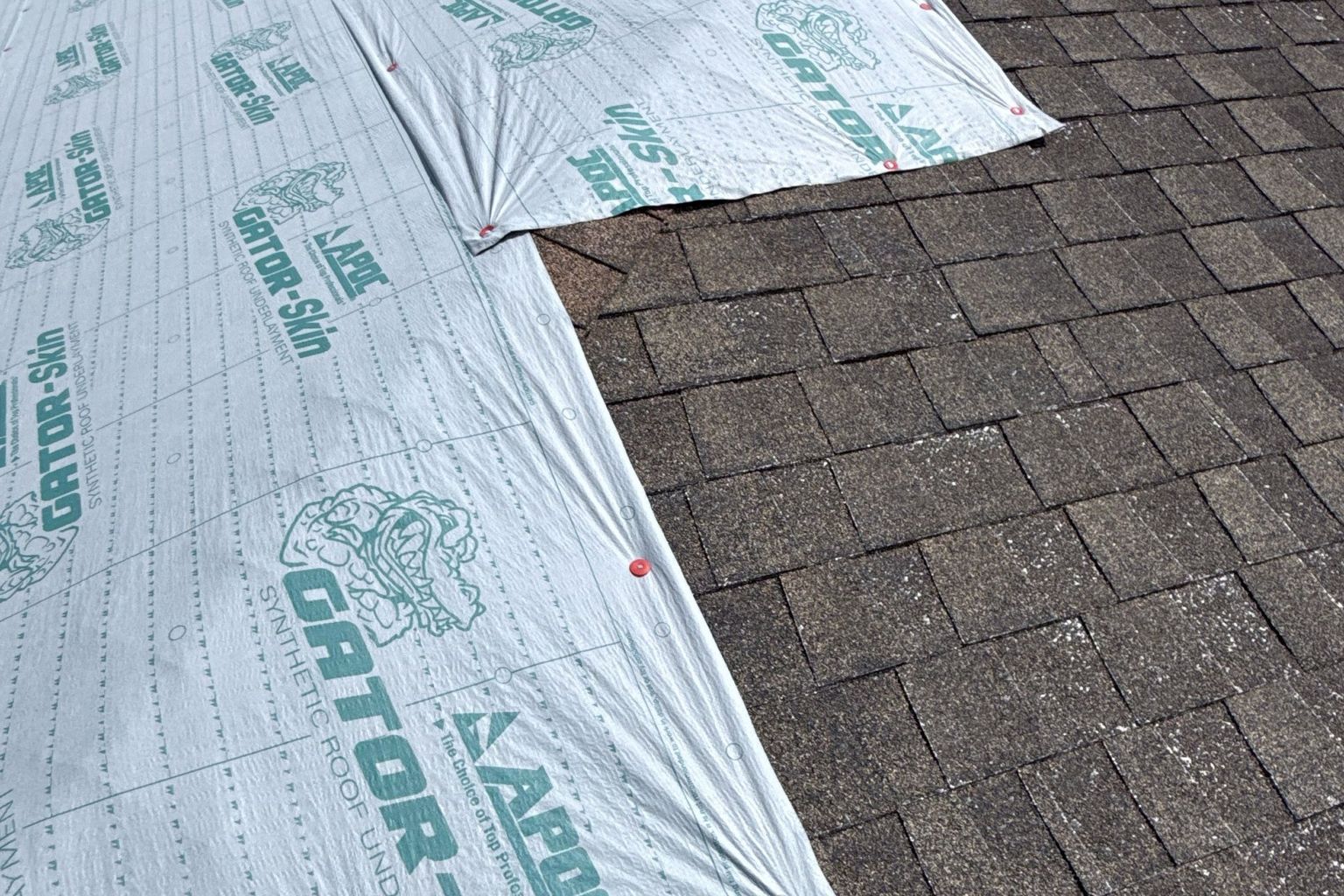 A shingle roof partly dried in with synthetic underlayment while repairs continue on a reopened property insurance claim