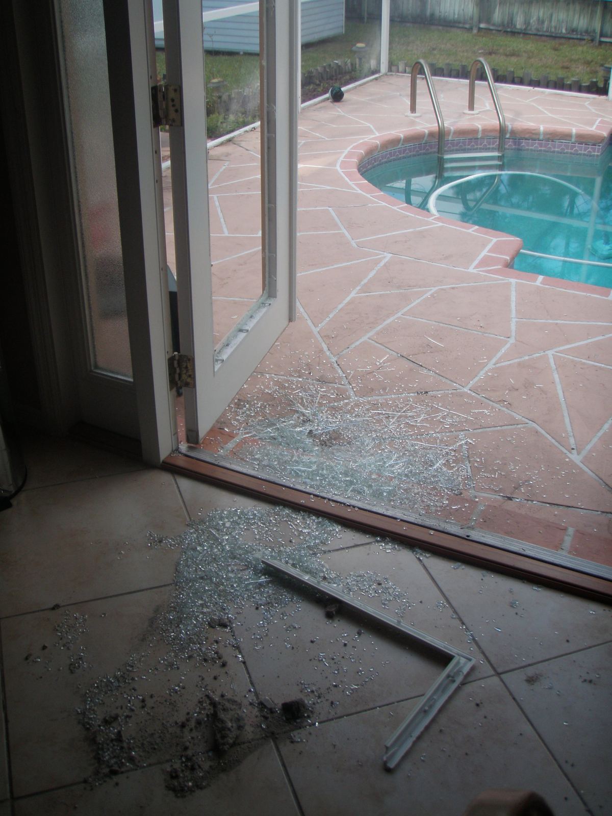 Shattered sliding patio door at a Florida pool home after a break-in