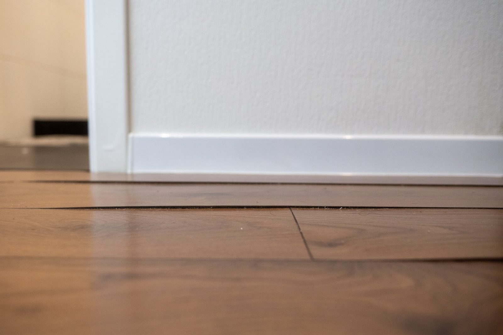 Wood flooring warped and lifting at the baseboard from water damage