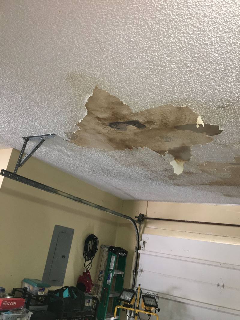 Peeling paint and ceiling damage from a water leak in a garage