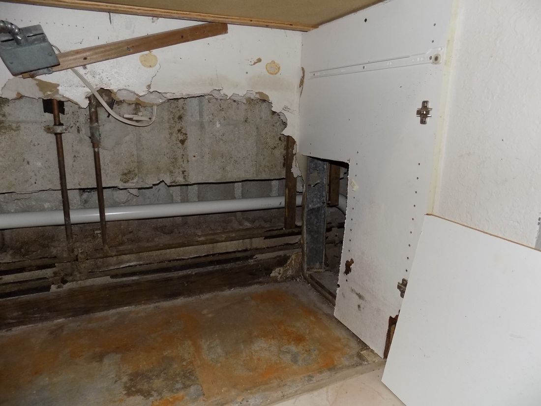 Wall and floor behind a sink cabinet damaged by a long-term pipe leak — the kind of claim Homeland handles for Long Branch, NJ property owners