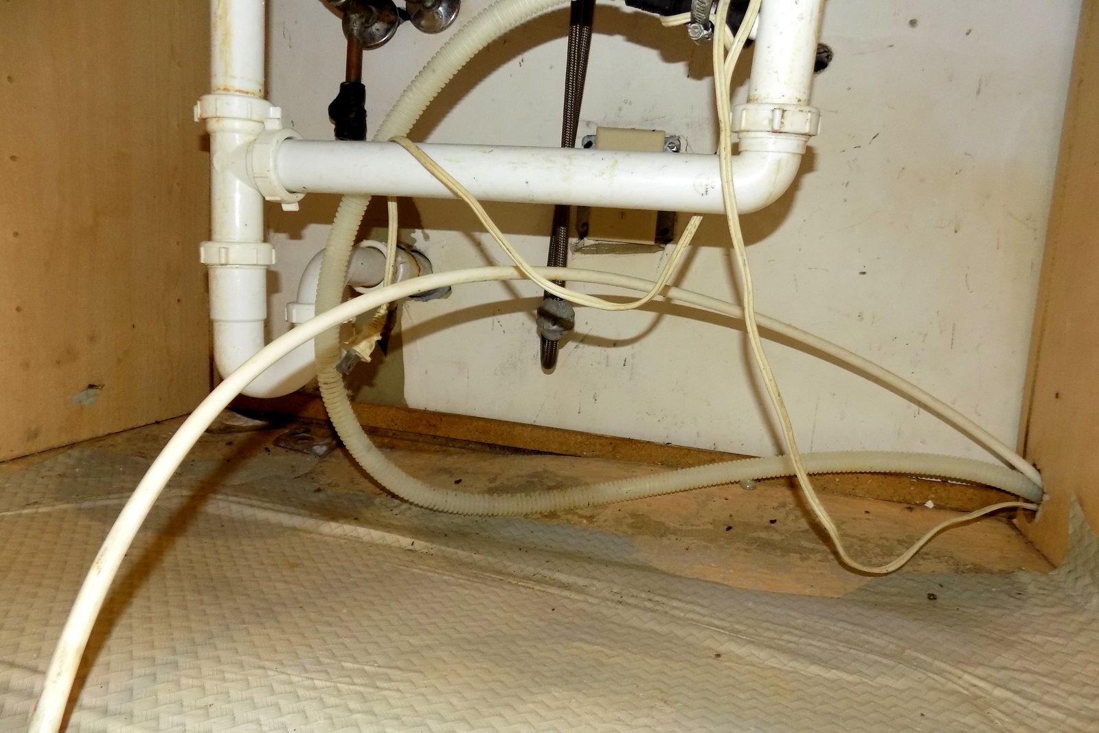 Piso de gabinete manchado de agua debajo del fregadero de una cocina con manchas oscuras de moho